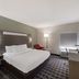 Quality Inn & Suites Irving Dfw Airport South guest room with king bed, desk, chair and floor lamp in Irving