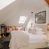 Karczma Rzym in Bydgoszcz attic bedroom with two beds, skylight, and hanging lamps