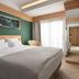 Mediterranean Hotel in Rhodes bedroom with king bed, green accent wall, and balcony doors with sheer curtains