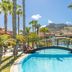 Pestana Porto Santo pool with arched bridge, palm trees and mountain backdrop in Porto Santo