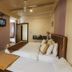 Hotel Bhagyalaxmi in Shirdi guest room with two twin beds, wall-mounted TV, AC, and ceiling fan