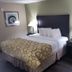 Baymont Inn & Suites Lake City guest room with king bed, bedside lamps and green armchair