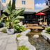 Hotel Mortagne in Boucherville courtyard with tropical plants, pond, patio seating and red umbrella