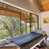 The Cavern in Bonjaneni: cozy room with single bed, wicker chair, and windowed forest views