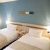 Karasuma Kyoto Hotel guest room with two twin beds, blue accent wall, and window light in Kyoto