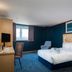 Travelodge Dartford room with king bed, chair, desk, and window view