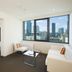 City Tempo Melbourne apartment with city skyline view, white sofa, chair and glass coffee table
