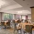 Sheraton Suites Akron Cuyahoga Falls dining room with round tables and large windows overlooking greenery