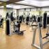 Chairman's Resort Bengaluru gym with weight machines and benches on a wood-floored fitness room