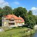 Ekesparre Boutique Hotel in Kuressaare beside a calm riverside with lush trees and a blue sky