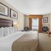 Best Western Plus St. Albert guest room with king bed, wall-mounted TV, and sitting area