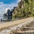 Pp Nice Beach Resort in Ko Phi Phi with a sandy beach, lounge chairs, boats, and limestone cliffs