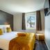 Aparthotel Ons Epen, Epen: modern hotel room with king bed, patterned accent wall, window and wall-mounted TV