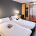 ibis Nantes La Beaujoire Parc Expo room with twin beds, hanging lights, desk, and window view in Nantes
