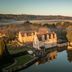 Schlosshotel Münchhausen in Aerzen beside a reflective moat, surrounded by autumn trees and fields
