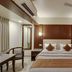 Hotel Centra-Ahmedabad in Ahmedabad guest room with bed, wood-paneled headboard, desk, and ceiling fan