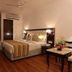 Hotel Impress By Rmr Hotels in New Delhi features a guest room with king bed, desk, and warm lighting