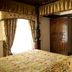 Marygreen Manor Hotel in Brentwood bedroom with four-poster bed, floral bedding, and adjoining sitting area
