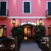 Hotel Splendid Mare in Laigueglia, pink facade with arched entrance, balconies, and lit lanterns at dusk.