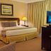 Herald Suites Solana Makati guest room with king bed, desk, and TV by curtains