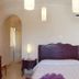 Masseria Pelosella B&B in Fasano, bedroom with carved wood headboard, bedside lamps, and arched doorway