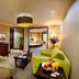 Millennium Hotel Sirih Jakarta suite living room with sofa, coffee table, and bedroom view in Jakarta
