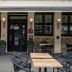 Outdoor seating at Logis -Hotel & Restaurant De La Place in Seulline, with entrance and stone facade.