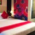 Ayara Grand Palace Hotel in Phitsanulok, a neatly made bed with red accent pillows beside a floral wall