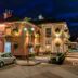 The Railway Inn in Brixham at night, a warmly lit corner hotel with hanging flower baskets and parked car