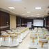 Meeting room at Hotel Impress By Rmr Hotels in New Delhi with rows of white chairs facing a projection screen