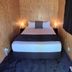 Waitomo Top 10 Holiday Park room with a double bed, bedside lamps and wood-paneled walls in Waitomo