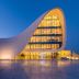 Sultan Inn Boutique Hotel in Baku, modern curved glass hotel exterior glowing at dusk