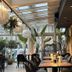 Hotel Arte in Brzeg dining area with tables, black chairs, skylight ceiling and indoor plants