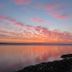 The Bay Horse Hotel And Restaurant in Ulverston overlooking a calm bay at sunset with pink clouds.