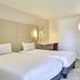 greet Hotel Versailles - Voisins Le Bretonneux guest room with twin beds, desk and green closet area