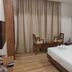 Hotel G Shy Bhopal guest room with bed, wooden chairs, small table and curtains