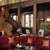 Schlosshotel Münchhausen in Aerzen: elegant lounge with red sofas, grand wooden staircase, and tall windows