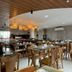 Hotel Gogó da Ema dining area in Maceió with wooden tables, chairs, and warm pendant lights
