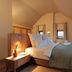 Hochblauen Hotel in Badenweiler, cozy attic room with king bed, bedside table, and wall-mounted TV