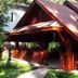 Royal Phawadee Village Patong wooden villa with red roof and shaded porch amid tropical greenery