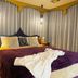 The Retreat at Froog Moore Park in Tamworth features a plush bed with purple bedding and hanging pendant lights.