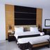 Grand Daira Hotel Palembang room with king bed, desk, chair and black-and-wood headboard in Palembang