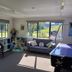 Waitomo Top 10 Holiday Park lounge with sofa, chair, children's play area and large windows to grassy outside
