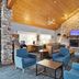 AmericInn by Wyndham Wisconsin Dells lobby with stone fireplace, wood ceiling, and blue seating