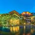 Hakka park International Hotel in Meizhou with lit exterior, palm trees, and reflection pool at dusk