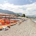 Lims Bona Dea Beach Hotel in Kemer with sun loungers on a pebbly beach beside calm sea and pier