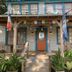 Blue Moon Guest House in Lafayette with a porch, rocking chairs, potted plants, and colorful flags