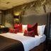 Eglinton Arms Hotel, Glasgow guest room with patterned wallpaper, large bed and red accent pillows