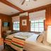 The Lodge on Lake Lure room with wood-paneled walls, striped bed, and windows overlooking Lake Lure.