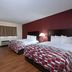 Red Roof Inn Warrenton guest room with two beds, wood-look floors, burgundy accent wall and TV